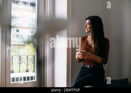 Durchdacht durch das Fenster schauen, während man in der Pause Kaffee im Büro genießt Stockfoto