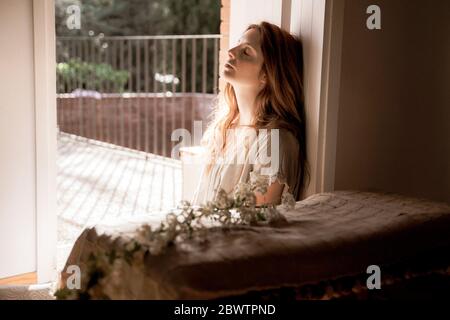 Junge Frau mit geschlossenen Augen entspannt zu Hause Stockfoto