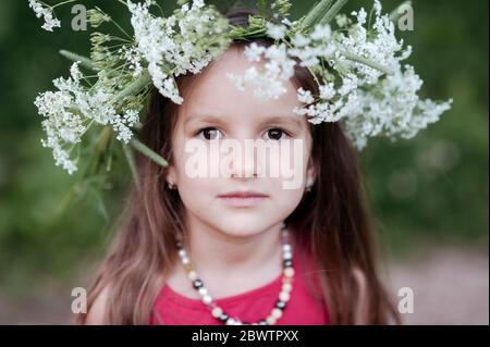 Portrait von niedlichen Mädchen tragen weiße Blumen im Park Stockfoto