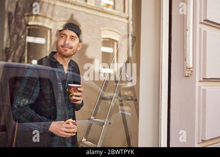 Mann, der die Lage des Ladens renoviert, Kaffee trinkt und