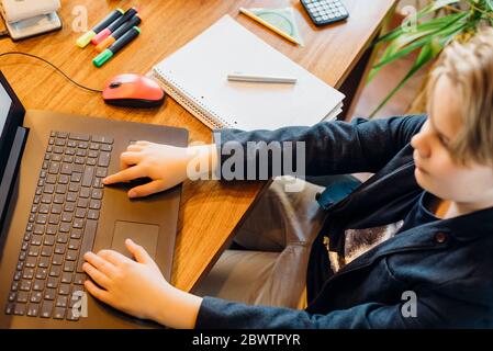 Junge, der mit einem Laptop am Schreibtisch sitzt Stockfoto
