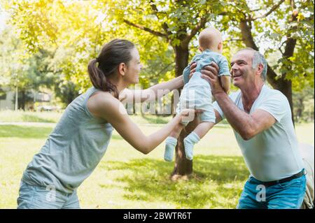 Älterer Mann verbringt Zeit mit seiner erwachsenen Tochter und seiner Enkelin in einem Park Stockfoto
