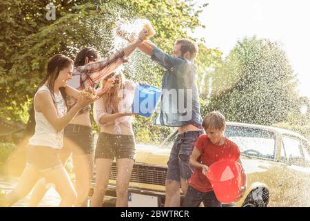 Gruppe von Freunden waschen gelben Oldtimer im Sommer Spaß Stockfoto