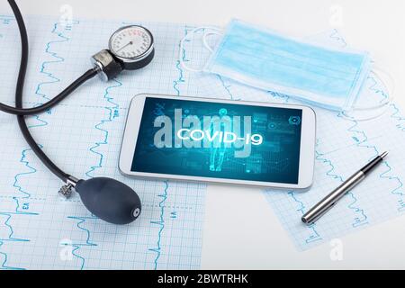 Tablett-pc und Arztwerkzeuge mit COVID-19-Beschriftung, Coronavirus-Konzept Stockfoto