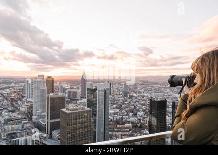 Deutschland, Hessen, Frankfurt, Frau, die die Innenstadt bei Sonnenuntergang fotografiert Stockfoto