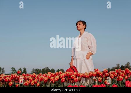 Porträt einer Frau mit geschlossenen Augen im Tulpenfeld stehend Stockfoto