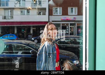 Porträt einer lächelnden Frau hinter dem Fenster in der Stadt Stockfoto