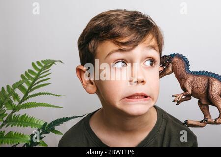 Portrait von kleinen Jungen mit Spielzeug Dinosaurier ziehen lustige Gesicht Stockfoto