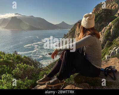 Frau, die die Aussicht von der Spitze eines Berges genießt, Chapman's Peak Drive, Südafrika Stockfoto