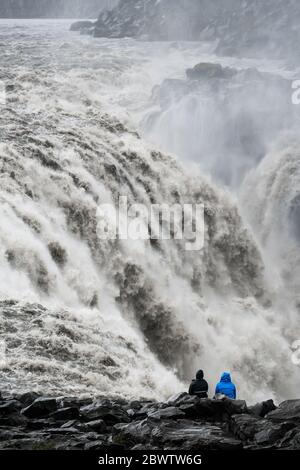 Nahaufnahme eines wütenden isländischen Wasserfalls mit einem schwarzen Felsstrand im Vordergrund Stockfoto