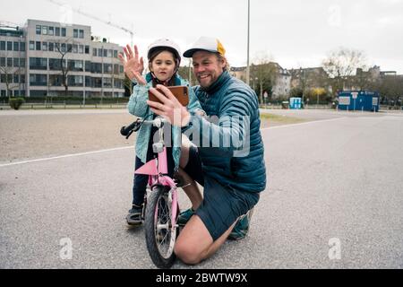 Glücklicher Vater und Tochter mit Fahrrad ein Selfie machen Stockfoto