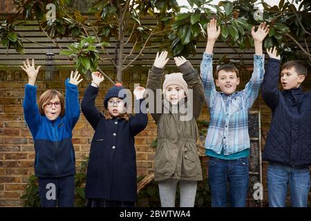 Gruppe von Kindern auf dem Schulhof, die während der Pause ihre Arme heben Stockfoto
