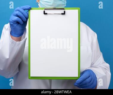 Doktor in einem weißen Gewand mit blauen medizinischen Handschuhen hält einen Ordner mit sauberen weißen Laken, Kopierraum Stockfoto