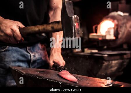 Messermacher bei der Arbeit, Stahlsplitter beim Hämmern Damast Stahl Stockfoto