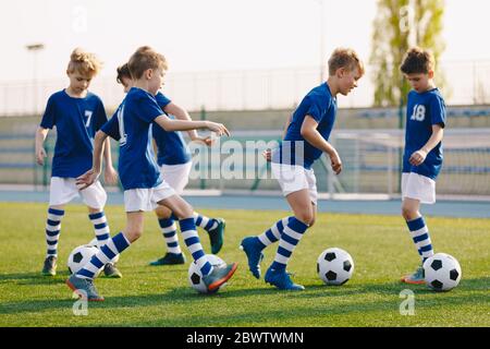 Jungen üben Fußball auf dem Schulfeld. 10 Jahre alte Kinder auf Fußball-Trainingskurs. Körpererziehungseinheit für Grundschulkinder Stockfoto