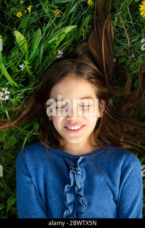 Portrait eines Mädchens mit geschlossenen Augen entspannend auf einer Wiese im Frühling Stockfoto