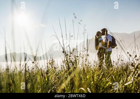 Ehepaar küsst sich bei Sonnenaufgang auf einer Wiese in den Bergen, Achenkirch, Österreich Stockfoto