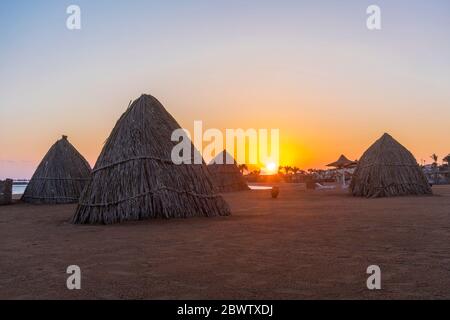 Ägypten, Hurghada, Strohhütten am Sandstrand der Bucht Sahl Hasheesh bei Sonnenaufgang