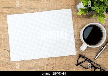 Leere Notizbuchseite auf dem Schreibtisch aus Holz. Draufsicht mit Kopierfläche, flachem Lay. Stockfoto