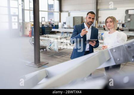 Geschäftsmann und junge Frau im Gespräch in einer Fabrik Stockfoto