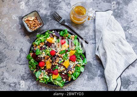 Teller gemischter Salat mit Feta-Käse, Rote Beete, Walnüssen, Mais-Salat, Himbeeren, Orangen und Pinienkernen Stockfoto