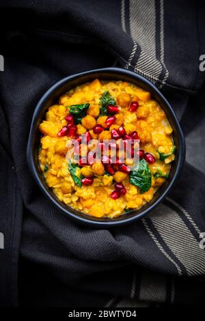 Schüssel mit veganem Curry mit roten Linsen, Süßkartoffeln, Spinat, gerösteten Kurkuma-Kichererbsen, Granatapfelkernen und Koriander Stockfoto