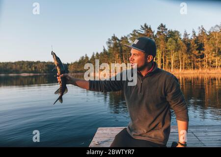 Junger Mann hält frisch gefangenen Fisch Stockfoto