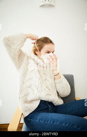 Portrait der blonden Frau trägt FFP2 Maske zu Hause Stockfoto