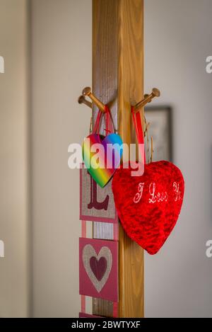 Dekorative rote Herzformen hängen an einem Holzpfosten Stockfoto