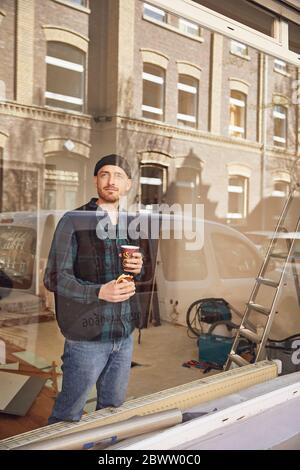 Mann, der die Lage des Ladens renoviert, Kaffee trinkt und