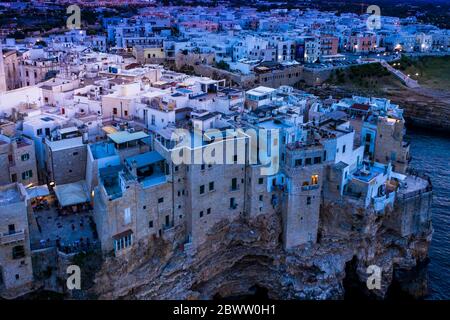 Italien, Polignano a Mare, Helikopter Blick auf Klippen und Gebäude der Küstenstadt in der Dämmerung Stockfoto