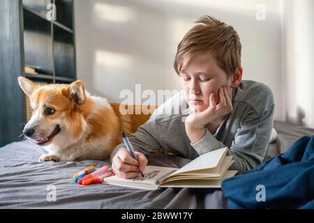 Portrait des Zeichnens Junge auf dem Bett mit seinem Hund liegen Stockfoto