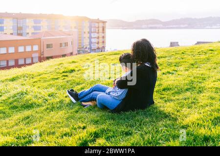 Mutter und Sohn entspannen sich auf einer Wiese bei Abenddämmerung Stockfoto