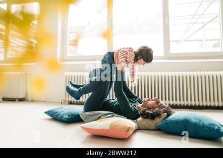 Glückliche Mutter spielt mit Tochter auf dem Boden Stockfoto