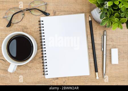 Leere Notizbuchseite auf dem Schreibtisch aus Holz. Draufsicht, flaches Lay. Stockfoto