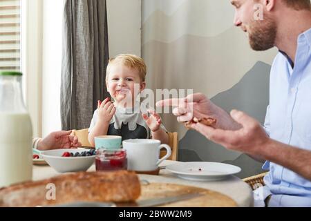 Portrait eines glücklichen kleinen Jungen am Frühstückstisch mit seinen Eltern Stockfoto