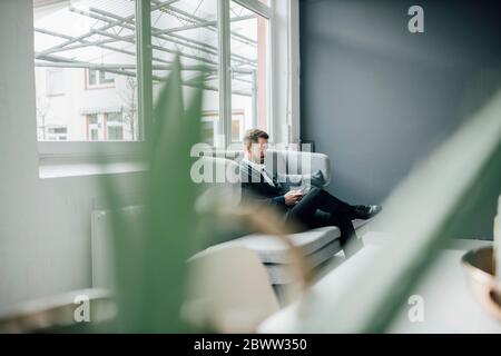 Geschäftsmann mit Smartphone auf der Couch im Büro sitzen Stockfoto
