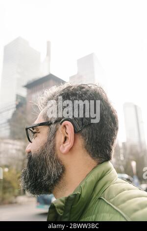 Mann mit Cochlea-Implantat vor Skycrapers, Frankfurt, Deutschland Stockfoto