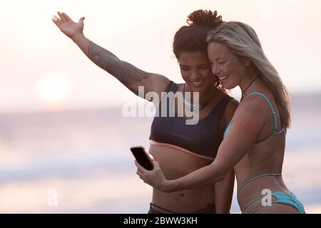 Zwei glückliche Frauen, die am Strand bei Sonnenuntergang Selfie machen, Costa Rica Stockfoto