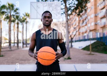 Junger Mann hält Basketball auf dem Basketballplatz Stockfoto