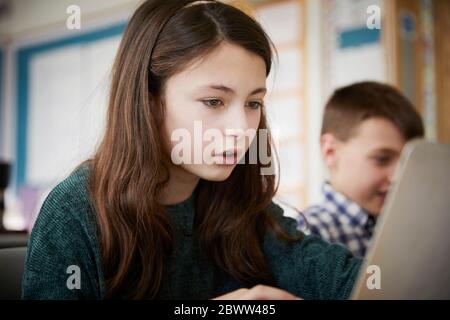 Mädchen und Jungen in einem Klassenzimmer während einer Lektion auf Laptops Stockfoto