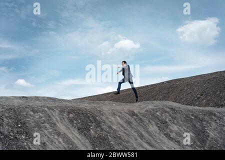 Reifer Geschäftsmann springt auf eine stillgediente Mine Spitze Stockfoto