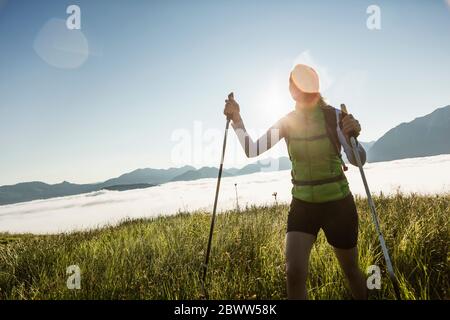 Frau beim Sonnenaufgang auf einer Wiese in den Bergen, Achenkirch, Österreich Stockfoto