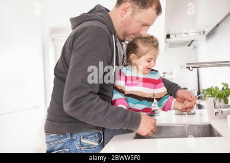 Vater und Tochter waschen sich in der Küche die Hände Stockfoto