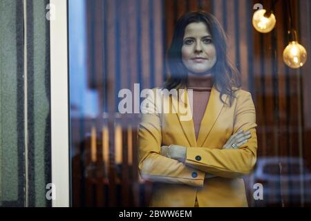 Porträt einer selbstbewussten Geschäftsfrau in gelbem Anzug hinter dem Fenster Stockfoto