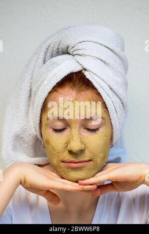 Portrait von Teenager-Mädchen mit Gesichtsmaske in einem Handtuch gewickelt Stockfoto