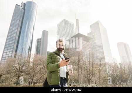 Mann mit Smartphone vor Skycrapers, Frankfurt, Deutschland Stockfoto