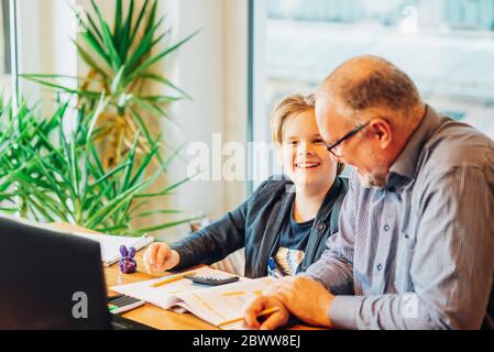 Vater hilft Sohn Hausaufgaben am Schreibtisch Stockfoto