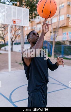 Junger Mann balanciert Basketball an seinem Finger Stockfoto