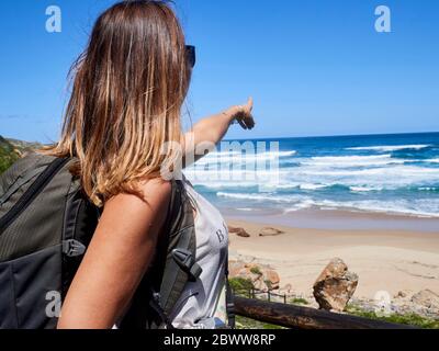 Rucksack Frau zeigt mit dem Finger auf den Ozean, Robberg Nature Reserve, Südafrika Stockfoto